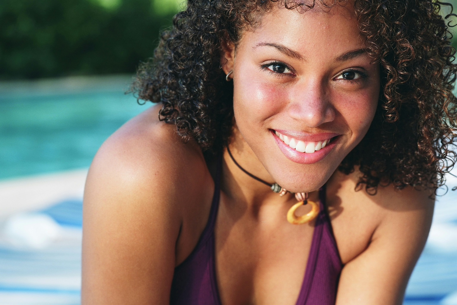 young black woman next to swimming pool, smiling nice teeth, teeth whitening San Diego, CA dentist