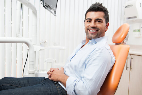 Hispanic man sitting in dentist chair in exam room, dental crowns Marlboro, NJ