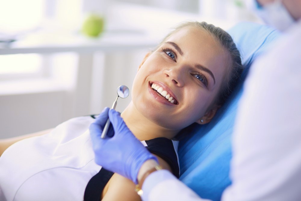 teen girl smiling looking up at dental hygienist as she gets examined, family dentist Marlboro, NJ