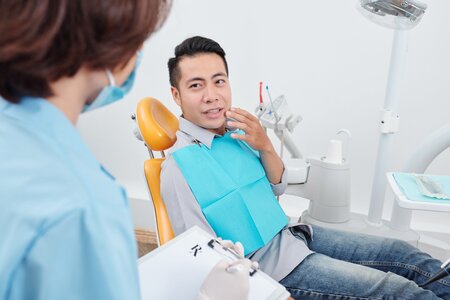 man sitting in dental exam chair, gesturing to his mouth in pain, needs root canal Windsor Locks, CT family dentistry