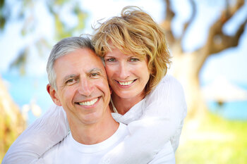 mature couple smiling outdoors near water, dental implants Tarzana, CA