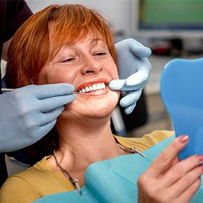 older red haired woman at dentist looking at teeth in mirror, San Jose, CA biomimetic dentistry