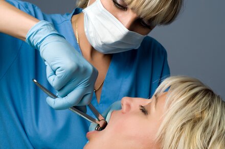 female dentist using dental pliers to extract tooth from woman's mouth, tooth extractions Old Bridge, NJ dentist 08857